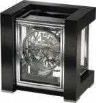 Ketchum Mantel Clock II by Howard Miller: A stylish and sophisticated timepiece for your home. This stunning mantel clock features a high polished gloss black piano finish, a see-through acrylic dial, a key-wound triple chime movement, and a nighttime chime shut-off option. It is a perfect addition to any modern home or office that values elegance, functionality, and personality. Learn more about the Ketchum Mantel Clock II and order yours today.